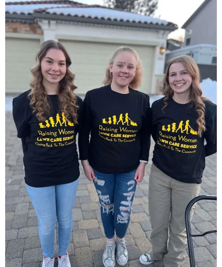 Three girls wearing black Raising Women shirts